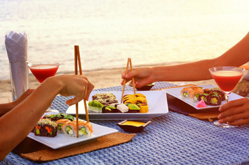 The dinner with japanese sushi roll set at the beach on the sunset