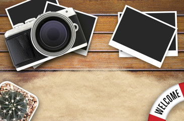 camera and blank photo frames on wooden table. top view, travel concept  