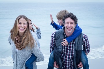 Happy parents carrying children at sea shore