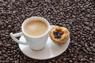 Taza de cafe con pastel de Belem sobre fondo de granos de cafe