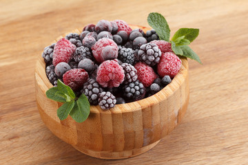 Frozen berries in wooden bowl, covered with ice