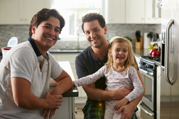 Obraz premium Male gay couple sitting with their daughter in the kitchen
