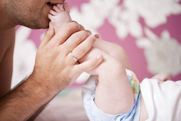 Close up, Father kisses his newborn son heels at home