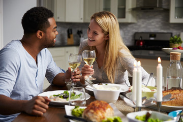 Romantic mixed race couple making a toast at meal in kitchen