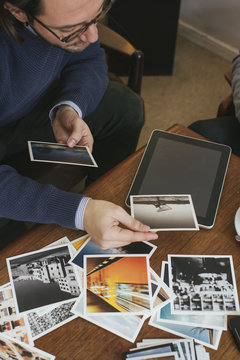 Man in a cafe looking at photo prints