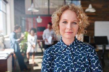 Female designer with colleagues in the background.