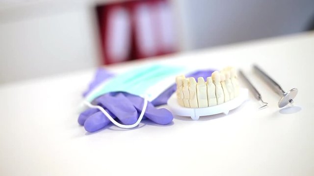 Zahnarztbesteck auf dem Schreibtisch mit Handschuhen und Mundschutz und einem Zahnabdruck
