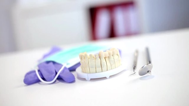 Zahnarztbesteck auf dem Schreibtisch mit Handschuhen und Mundschutz und einem Zahnabdruck