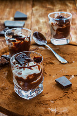 Ice cream with chocolate in small glasses on cocoa background.