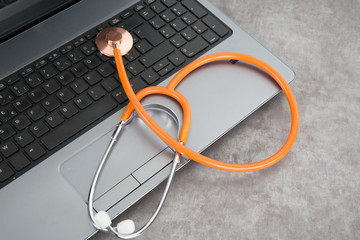 Medical stethoscope resting on laptop computer keyboard.