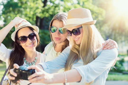 Selfie. Three attractive girls taking picture at summer holidays, girls with camera taking self-portrait on their travel vacation