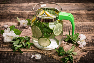 detox water with a lemon, lime and mint on a wooden table