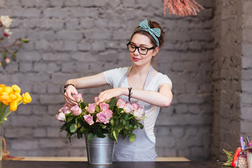 Beautiful woman florist arranging roses in bucket