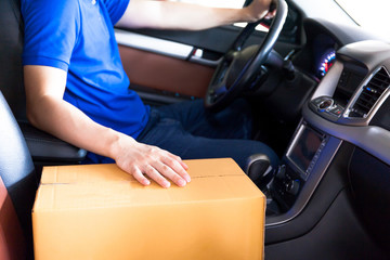 Delivery man driving a truck with cardboard package on the front