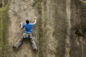 Athlete climbs on rock with rope.