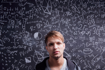 Student against a big blackboard with mathematical symbols