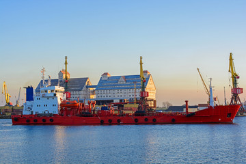 Commercial docks at sunset with a ship and cranes