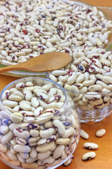 Colorful haricot beans in glass bowls on wooden background