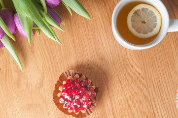 Violet tulips, cake and tea on the wood