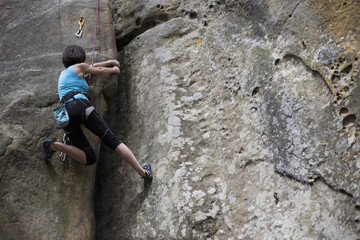 Athlete climbs on rock with rope.