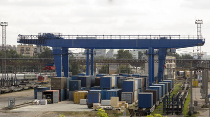 Freight trains on cargo terminal. Crane lifting up container