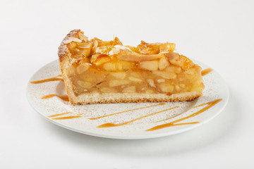 Delicious apple pie charlotte with caramel on the plate on white background. Close up side view.