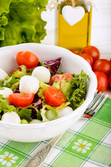Fresh vegetable salad with tomatoes and feta in white bowl.