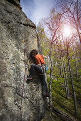 Athlete climbs on rock with rope.