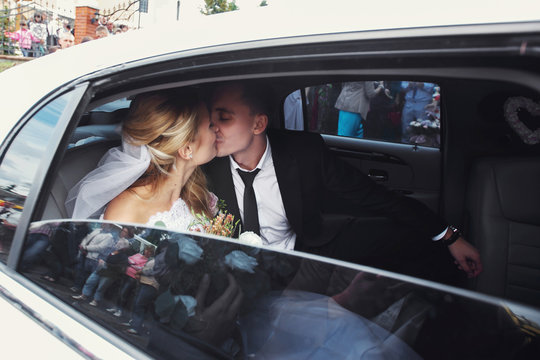 Happy romantic newlyweds kissing in wedding limo
