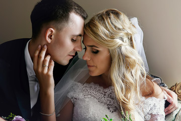 Romantic sensual newlyweds posing on luxury sofa face closeup