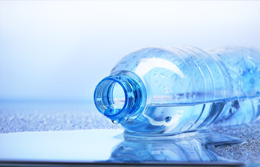 Drop of water falling from plastic bottle with reflection