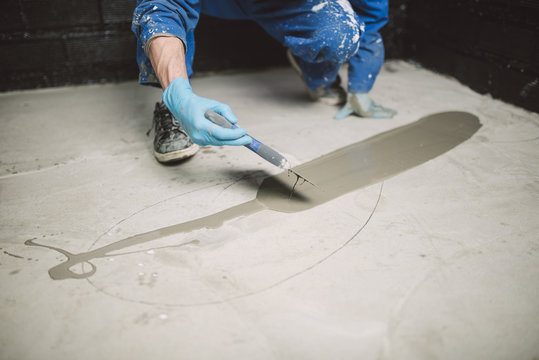 Bricklayer applying wet cement on floor