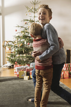 Two brothers waiting in front of Christmas tree looking at presents
