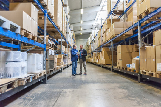 Two managers discussing packaging and shipment in storage hall