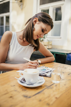 Austria, Vienna, Young woman sitting in Heurigen restaurant writing postcards