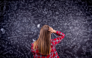 Student against a big blackboard with mathematical symbols