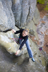 The girl climbs on the rock.