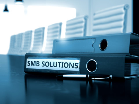 File Folder with Inscription SMB Solutions on Working Office Desktop. SMB Solutions - File Folder on Wooden Desktop. SMB Solutions - Business Concept on Blurred Background. 3D.