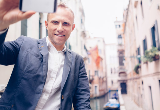 Smiling man take a selfie tourist photo on the Venice chanel bac