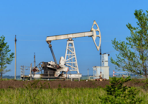 Old oil pumpjack on the summer field
