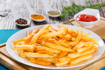 Tasty french fries on plate, on wooden table background