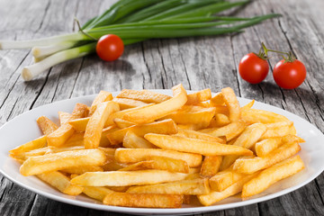 Tasty french fries on plate, on wooden table background