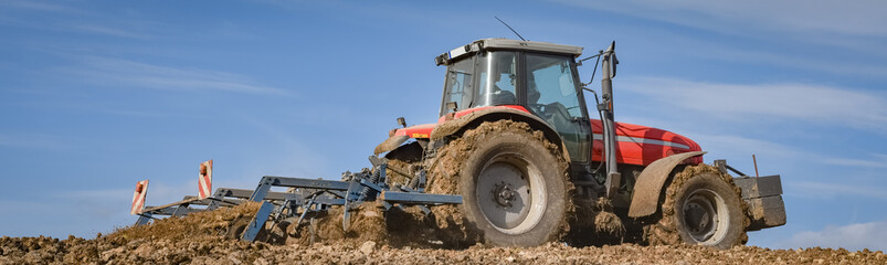 Fototapeta premium Ackerbau - Traktor bei der Bodenbearbeitung