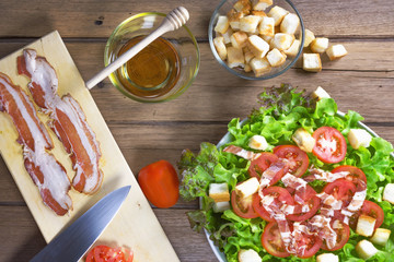 Salad with bacon, olives and tomatoes on wooden table. Top view