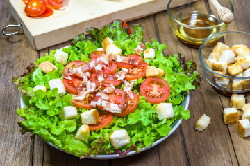 Salad with bacon, olives and tomatoes on wooden table. Top view