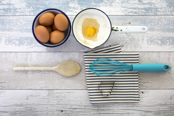 Eggs in a box with a whisk on a rustic wood table