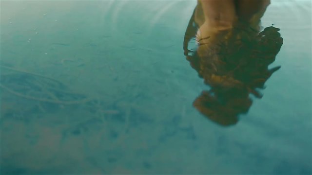 Reflection of beautiful young naked girl in the picturesque mountain lake Synevir in the Carpathians. Young nymph surrounded by  herd of little fishes. Slow motion shot