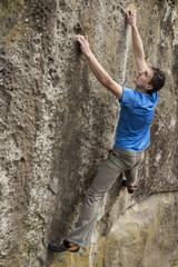 Athlete climbs on rock with rope.