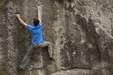 Athlete climbs on rock with rope.