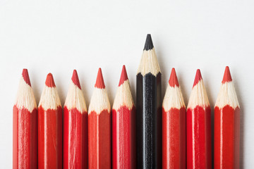 Group of red pencils and one black, individuality concept